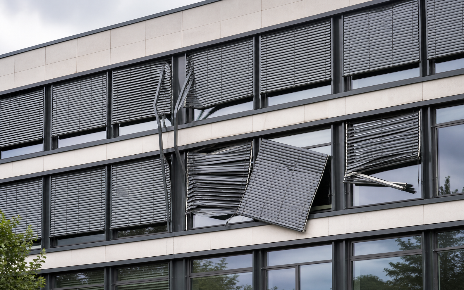 Moderne Fassade mit durch Wind verbogenen au&szlig;enliegenden Jalousien und besch&auml;digten F&uuml;hrungsschienen